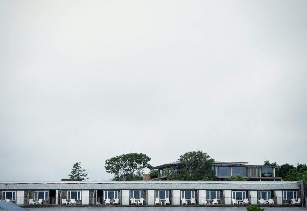 Outside view of beachside motel balconies with trees and a grey sky behind.